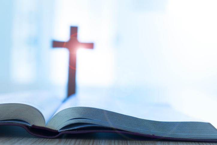 Rozłożona Biblia i krzyż usłane promieniami słońca